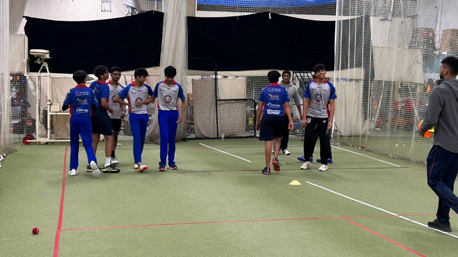 A coach instructing young players in a drill involving cones, medicine balls, and movement exercises, enhancing coordination and fitness for cricket.