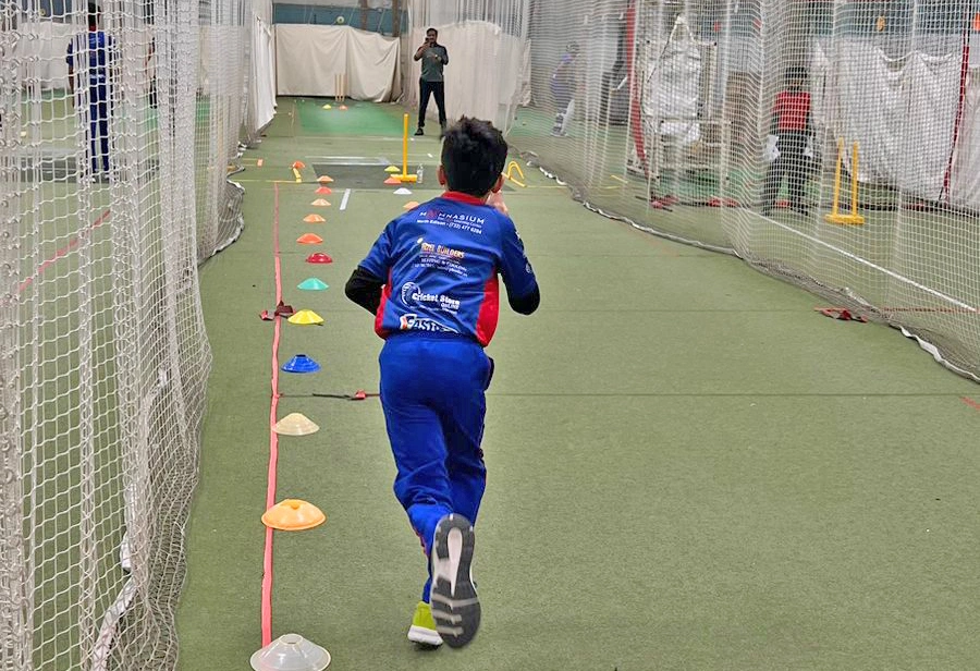 A young CricMax player running through a lane marked with training cones, improving agility and speed as part of cricket fitness drills.